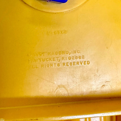 Orange toy with 'Hasbro, Inc.' branding and address on a orange background