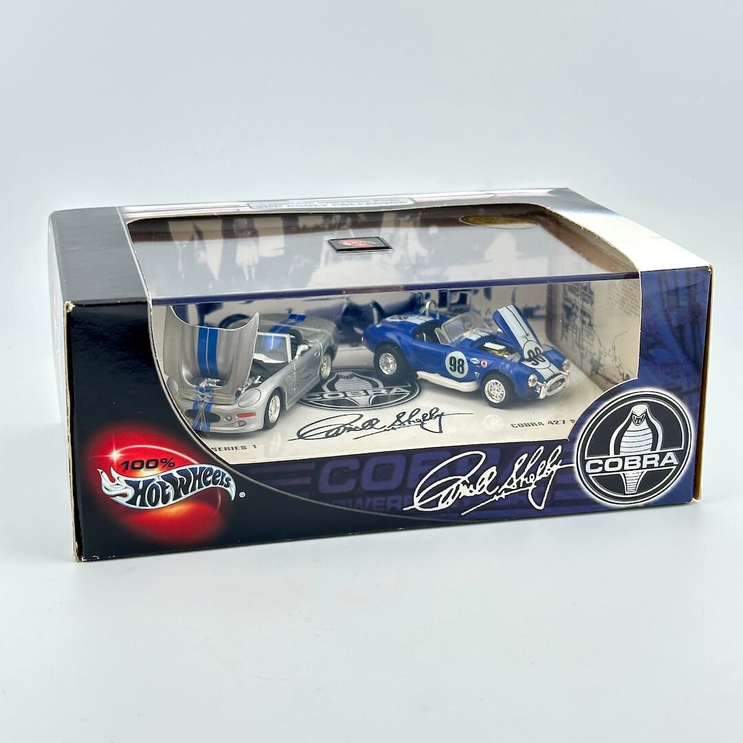 Hot Wheels collectible 1:64 scale model car set featuring two Cobra sports cars in a clear-top display box.