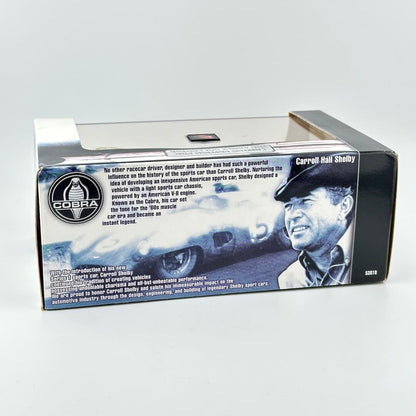 A boxed collectible model car package  with blue and white graphics, including a Cobra logo, & text about Carroll Shelby.