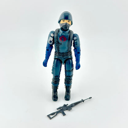 Action figure in blue outfit with gun accessory against white background. 