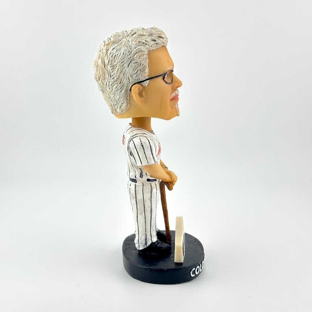 Bobblehead figure of a person in a striped uniform holding a bat on a white background