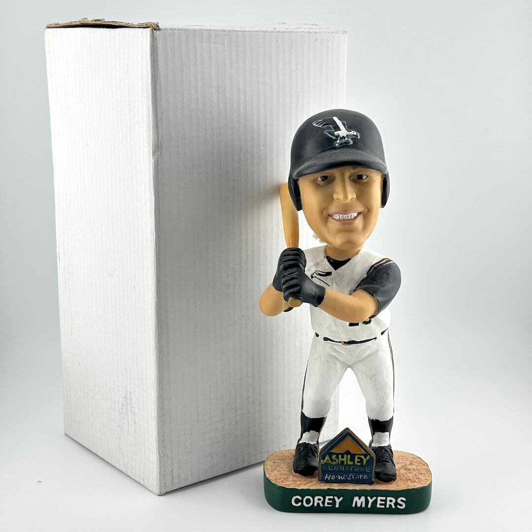 Baseball bobblehead figure of a player holding a bat, standing next to a cardboard box on a white background.