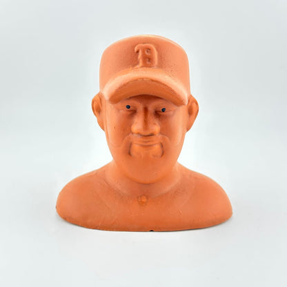Terracotta-colored bust of a man wearing a cap on a light gray background