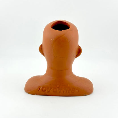 Terracotta-colored head-shaped object with 'TOYO TIRES' branding on a white background