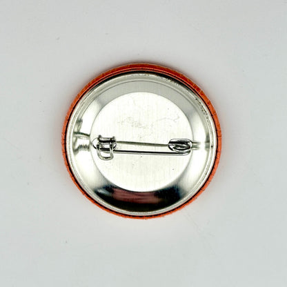 Round metal badge with a pin on a white background