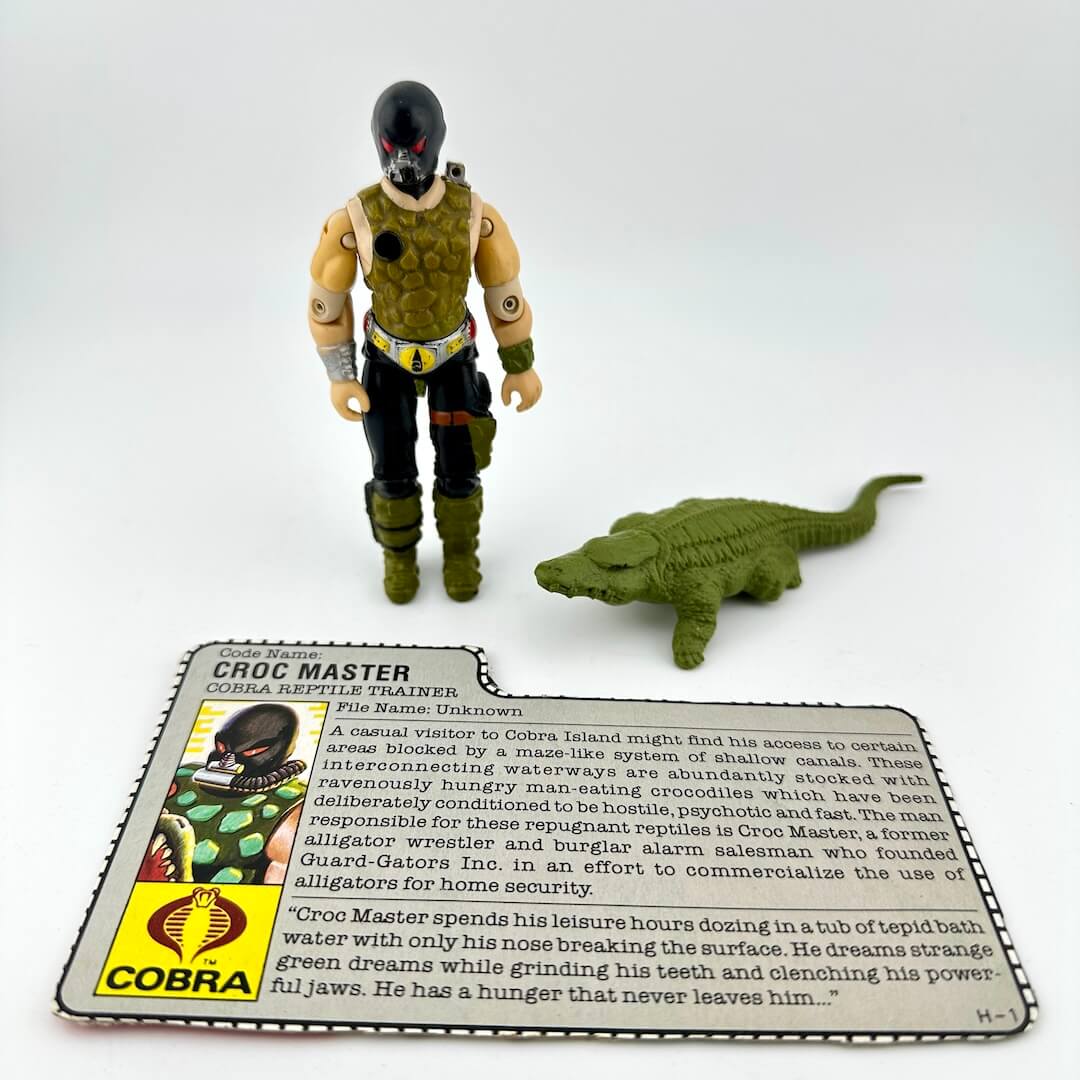 Toy figure of Croc Master with a card and small crocodile model on a white background