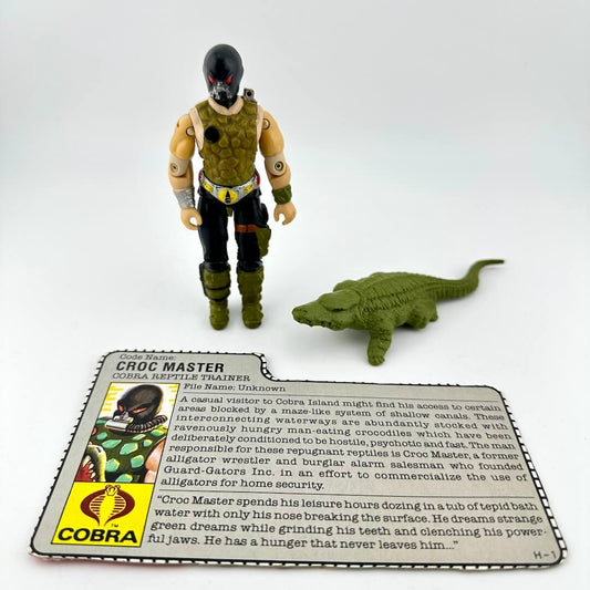 Toy figure of Croc Master with a card and small crocodile model on a white background