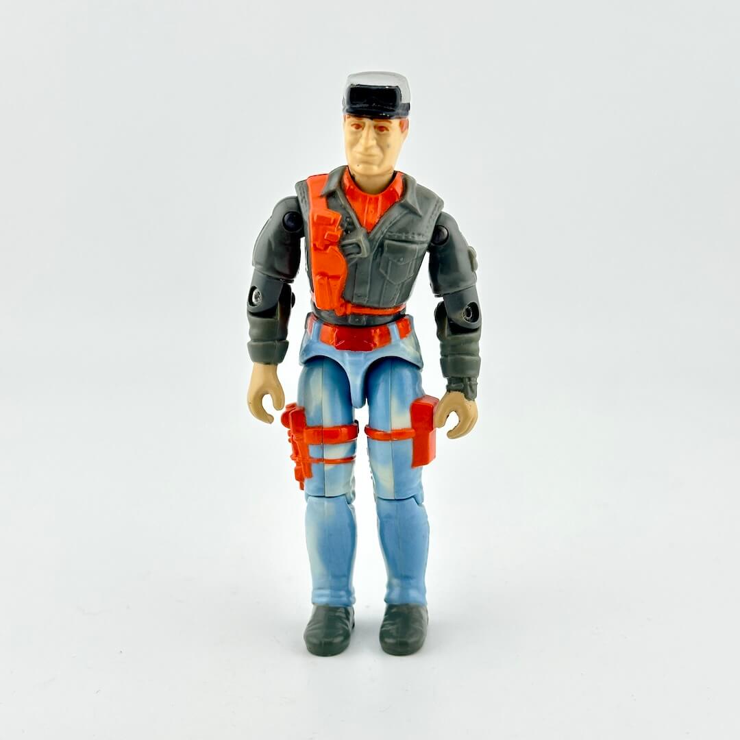 GI Joe action figure in faded blue pants and gray shirt with orange accents, photographed on white background. 