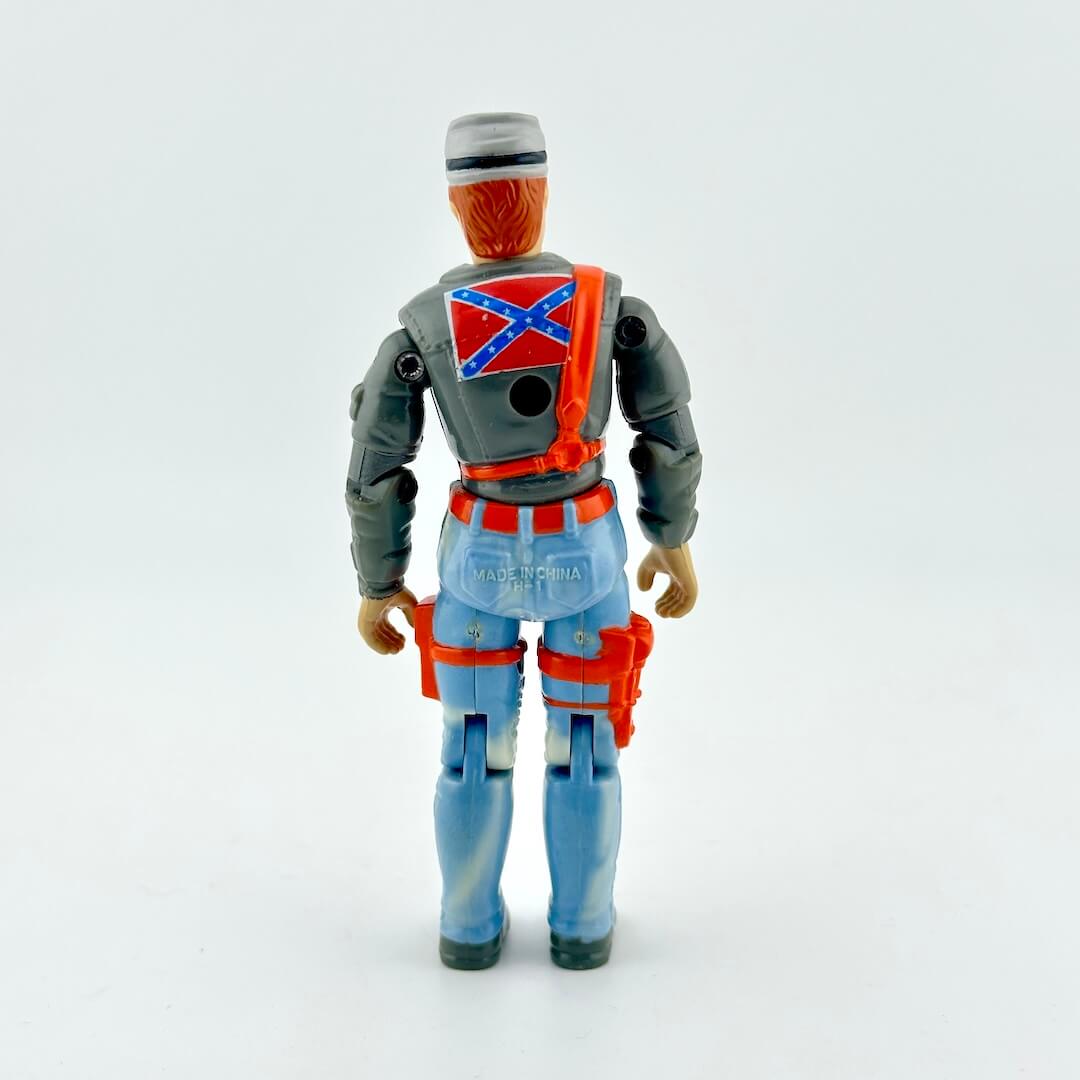 GI Joe action figure in faded blue pants and gray shirt with orange accents, photographed on white background. 