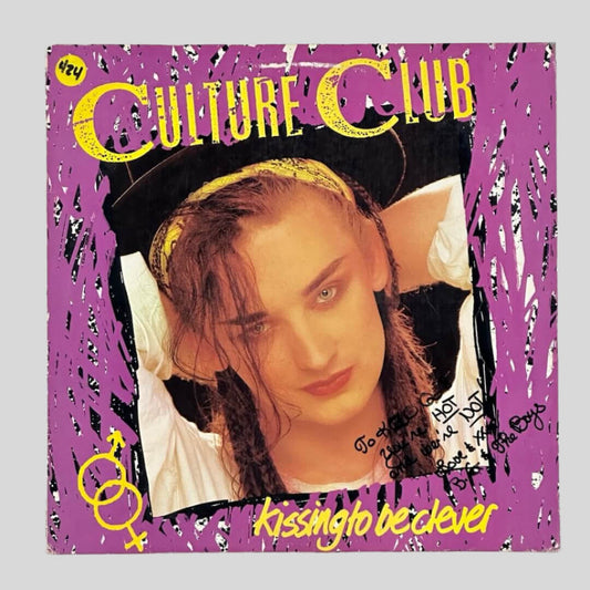 Front of record sleeve with purple background, image of girl in braids wearing a hat in center, yellow text.