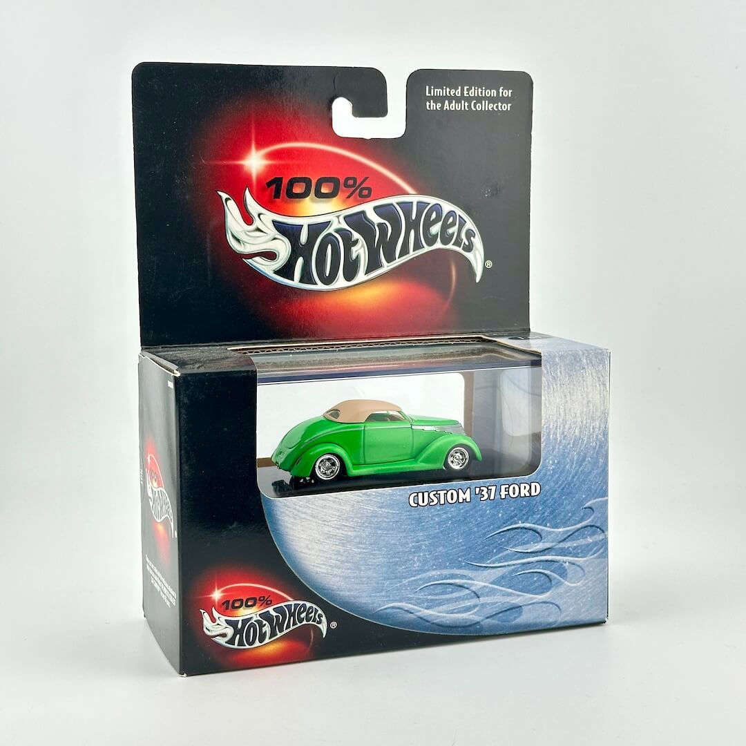 A Hot Wheels diecast car in its original retail packaging, featuring a green 1937 Ford custom car. 