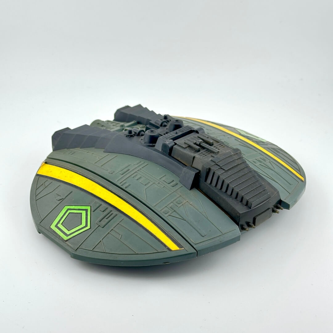 Toy spaceship model with green and yellow details on a white background