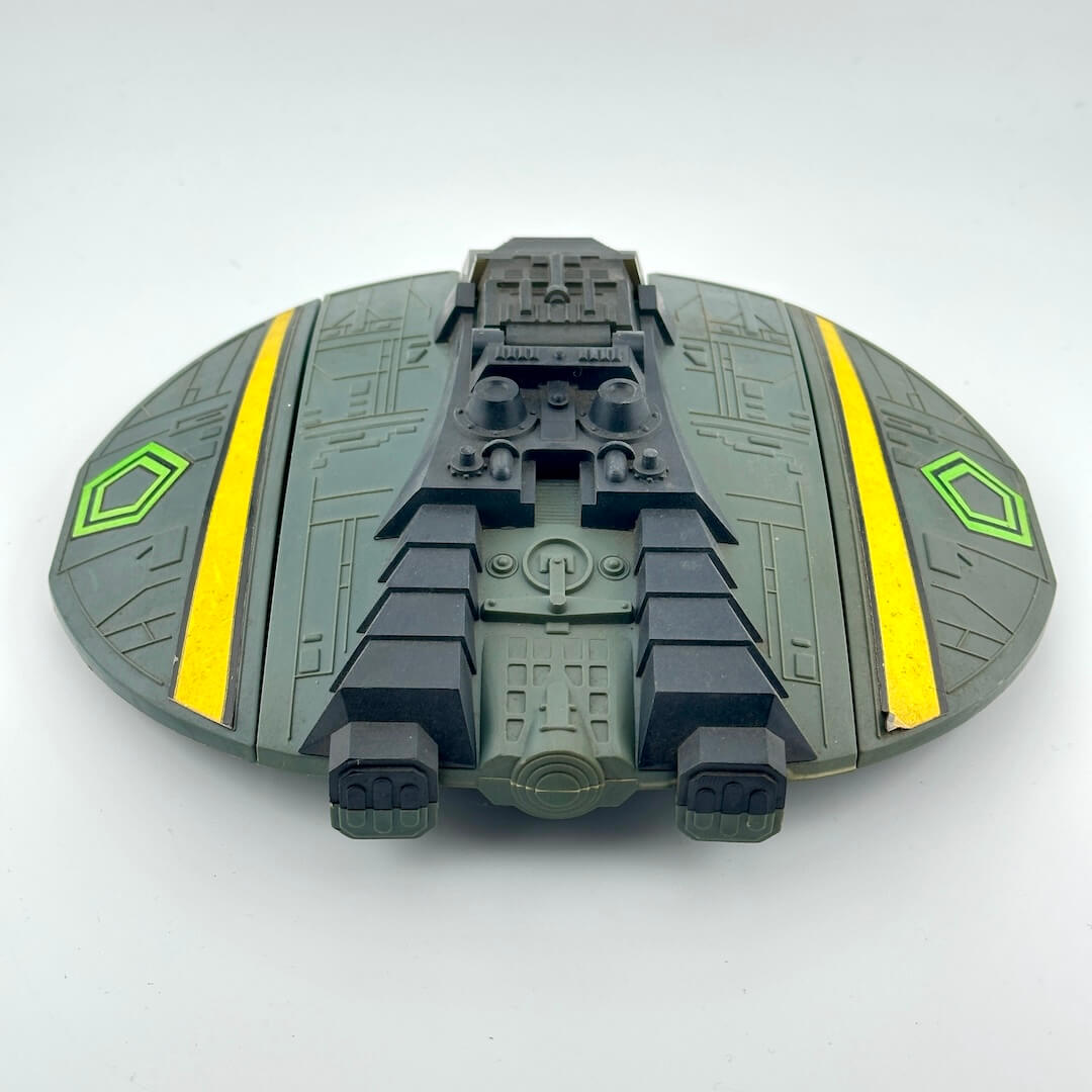 Toy spaceship model with green and yellow design on a white background