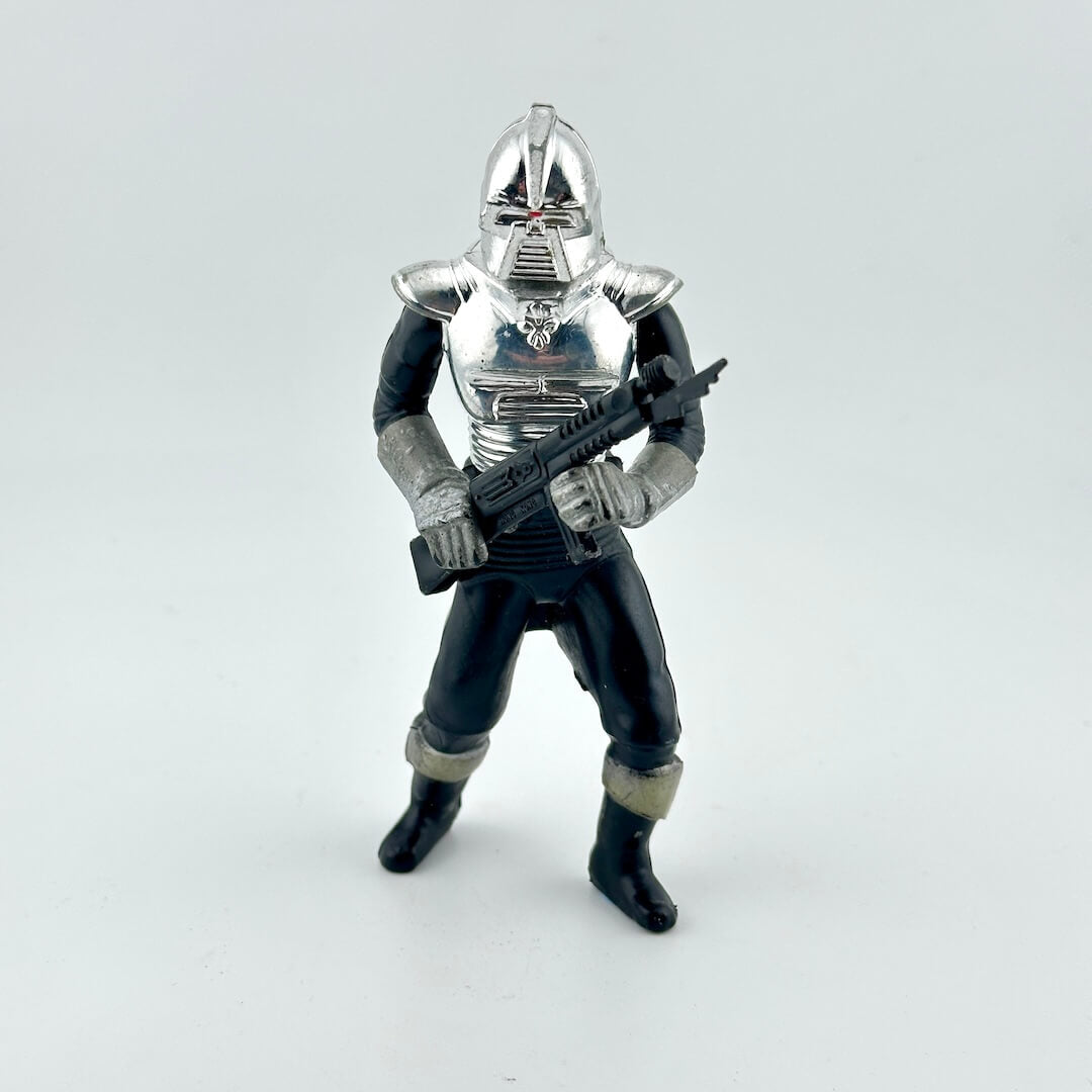 Toy figure of a character in silver armor holding a weapon on a white background