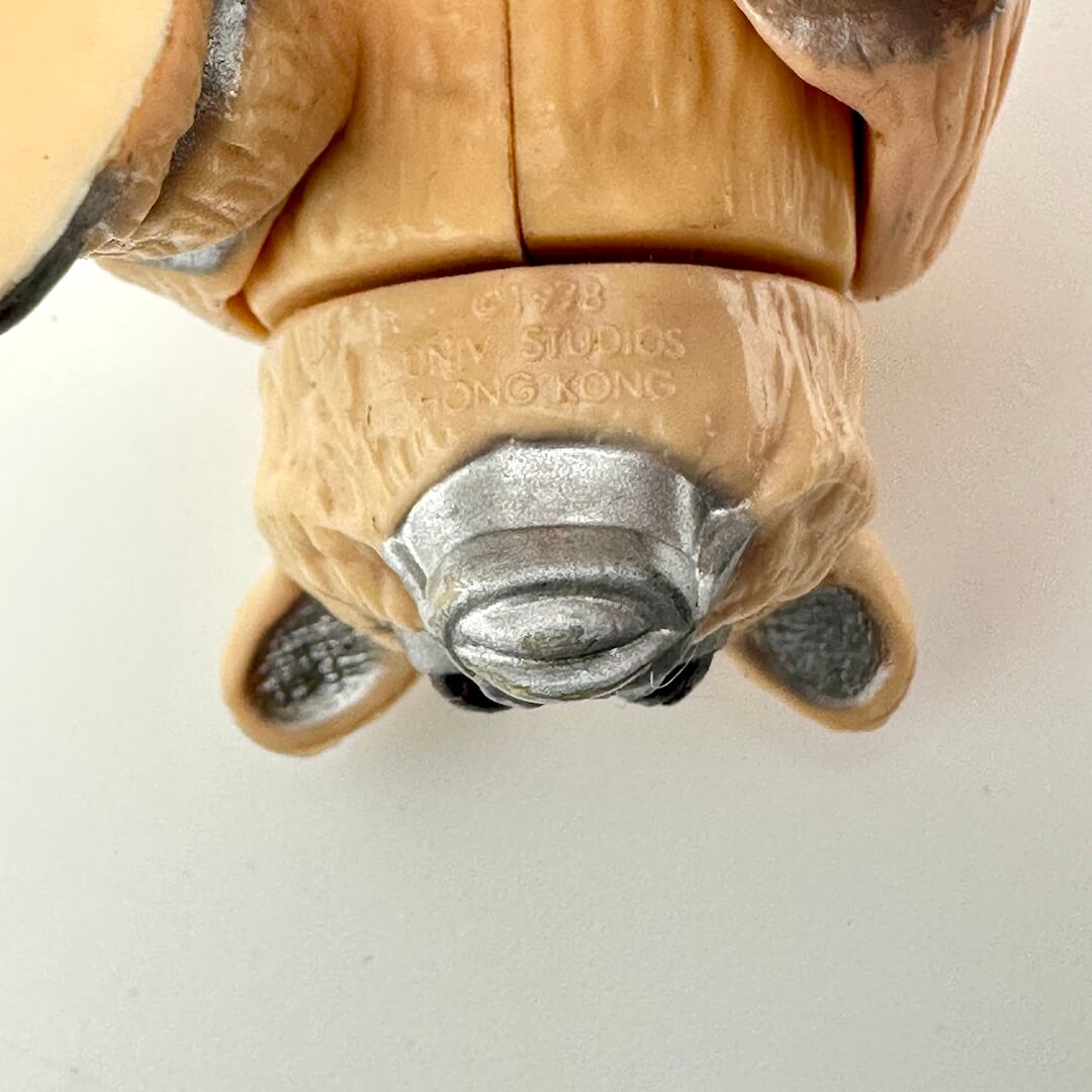 Close-up of a toy figure's head with  branding on a white background