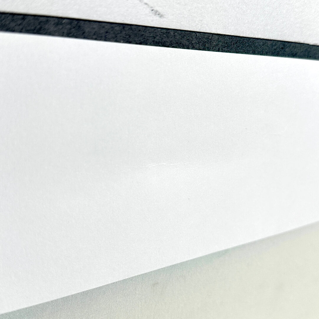 Side view of slight dent in border along bottom of print. 