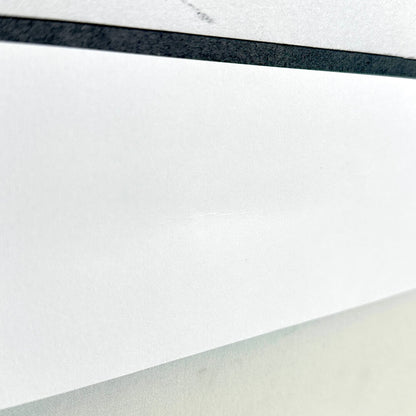 Side view of slight dent in border along bottom of print. 