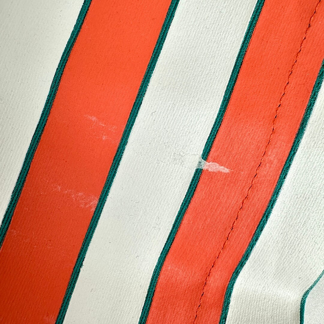 Close-up of a striped textile with alternating white and bright orange vertical stripes, showing a small white scratch.