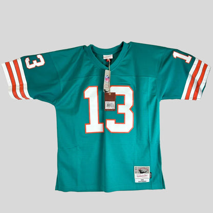 A teal Miami Dolphins football jersey with the #13 on the front, featuring white and orange sleeve stripes and a visible Mitchell & Ness tag.