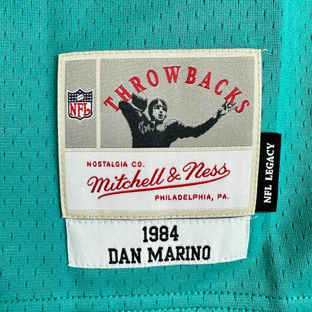 Close-up of a teal mesh sports jersey patch area showing an embroidered NFL patch with the text 'Throwbacks'