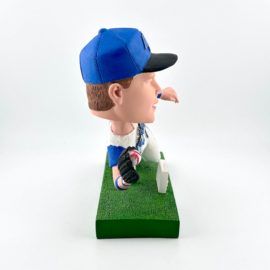 Bobblehead figure of a person wearing a blue cap and sitting on a chair with a white background