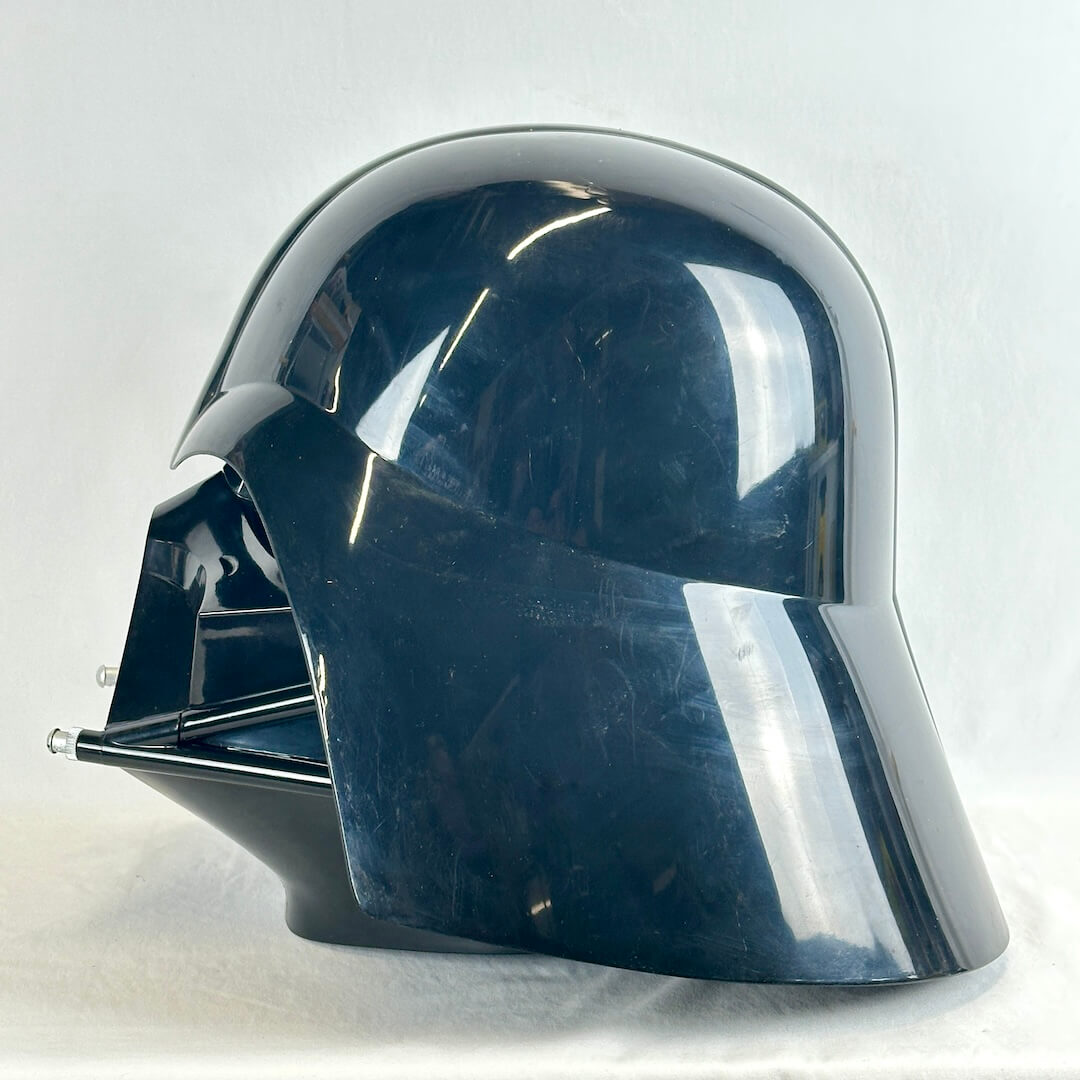 A glossy black Darth Vader helmet replica or costume headpiece, photographed against a light gray fabric backdrop.