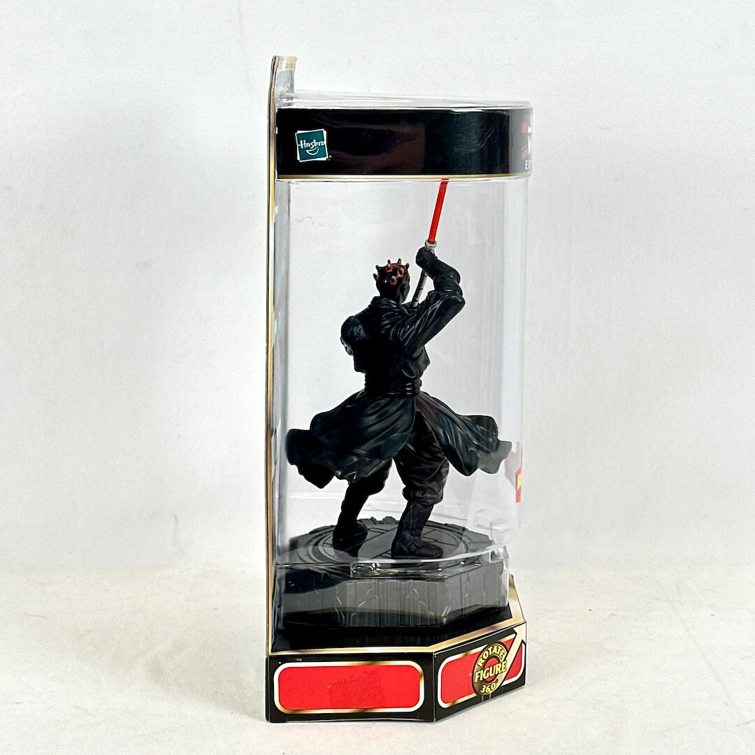Black figurine with a red lightsaber in a clear display case on a white background