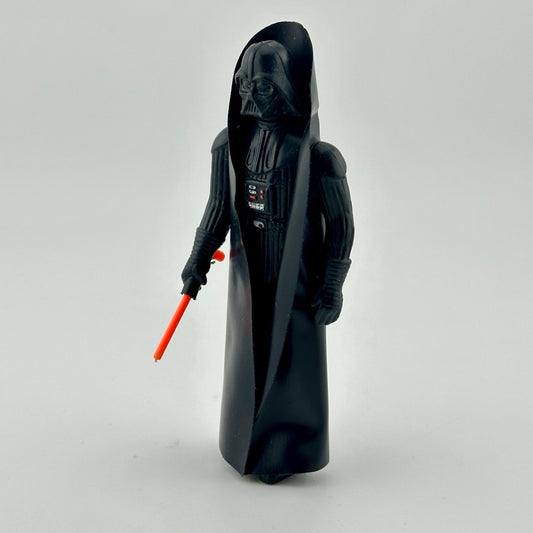 Action figure in all black, black helmet, & black cape, with red lightsaber emerging from right hand. 