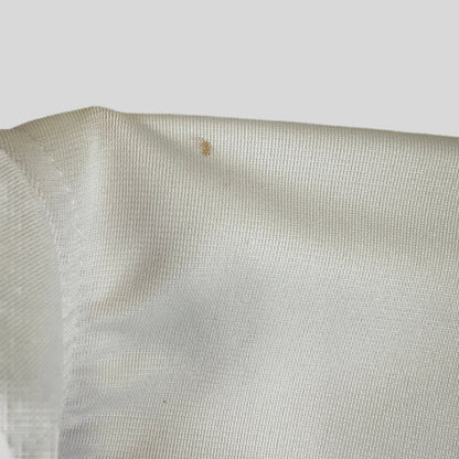 Close-up of a white fabric with a small brown stain on a light background