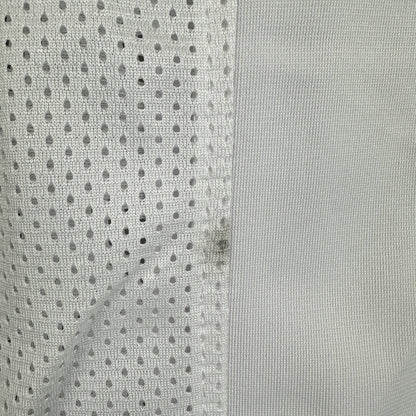 Close-up of a gray fabric with a mesh pattern and small black smudge on seam. 