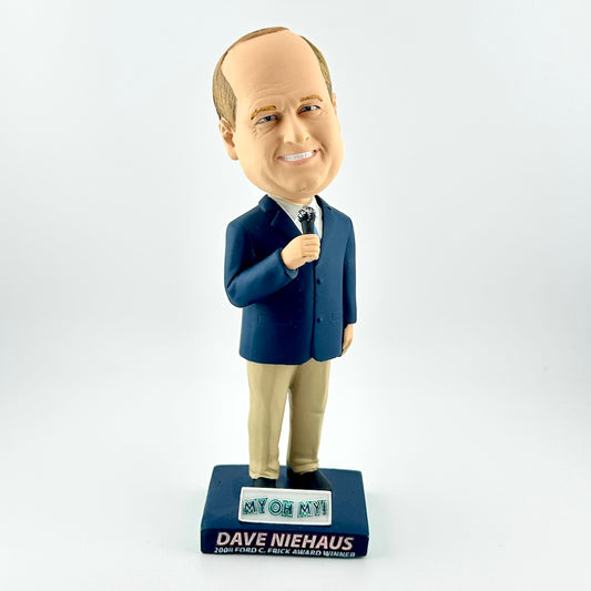 Bobblehead of a man in a suit holding a microphone on a white background