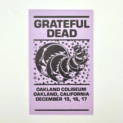 Purple rectangular card with "Grateful Dead" text at top with event dates along the bottom, central image of stealies. 
