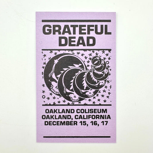 Purple rectangular card with "Grateful Dead" text at top with event dates along the bottom, central image of stealies. 