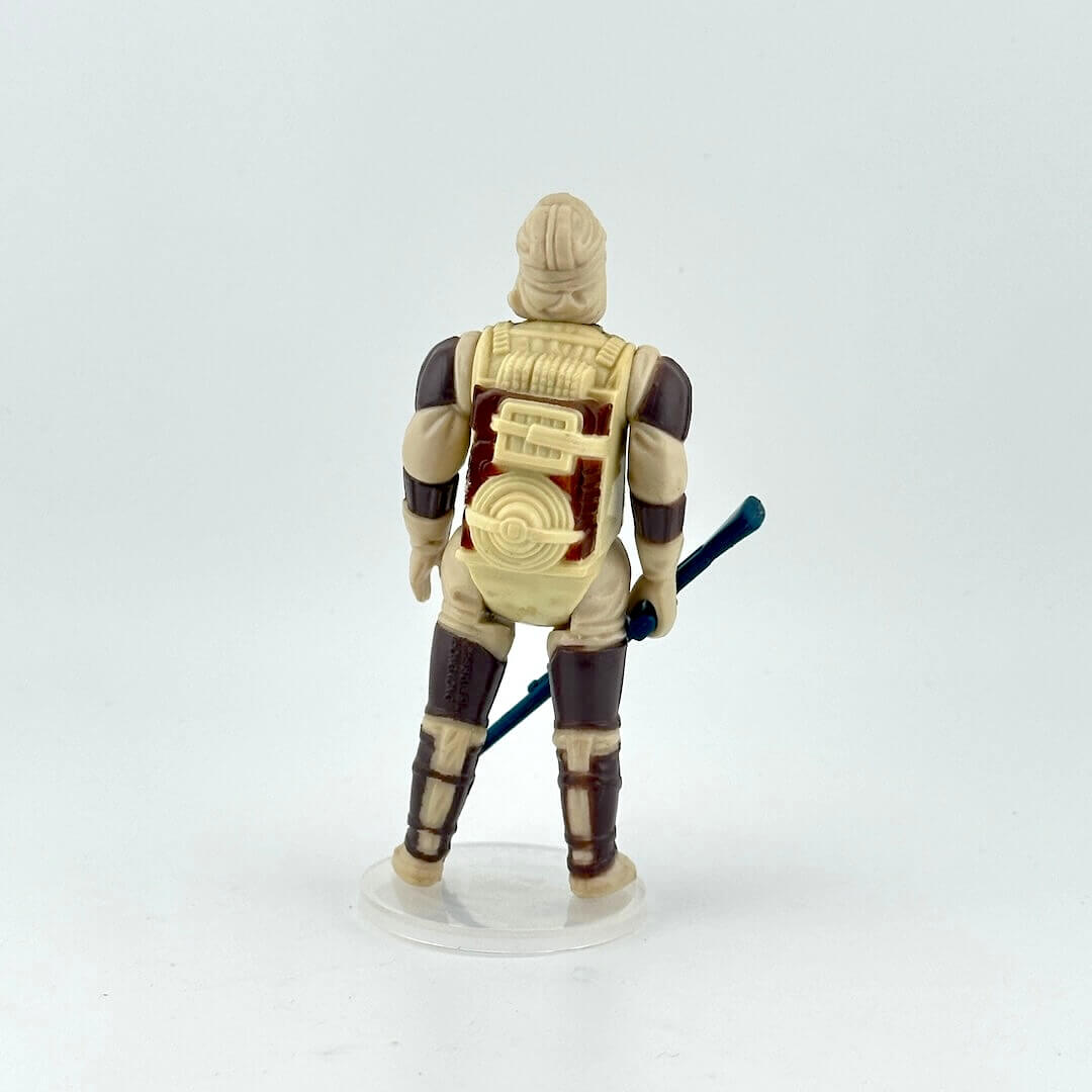 Action figure with a beige and brown outfit, holding a blue weapon on a white background