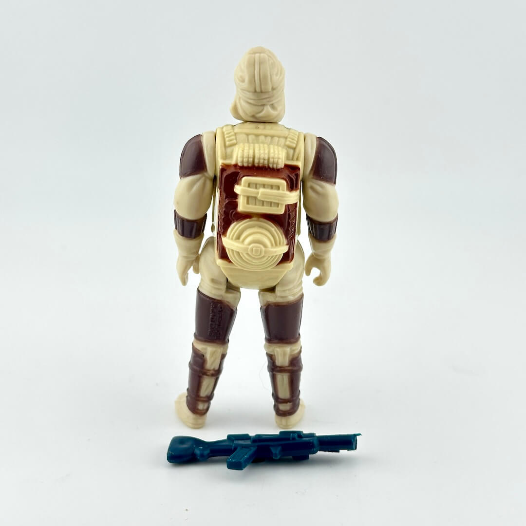 Action figure shown from the back, featuring a tan and dark brown armored design with a blue toy rifle accessory.
