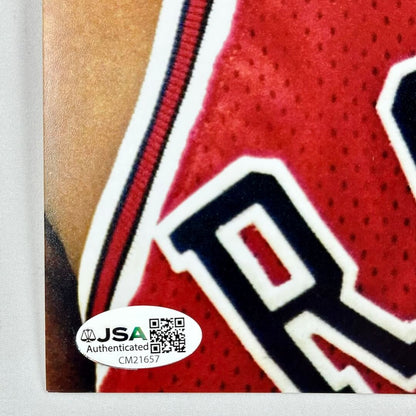 Close-up of a red sports jersey with a logo, featuring a JSA authentication label.