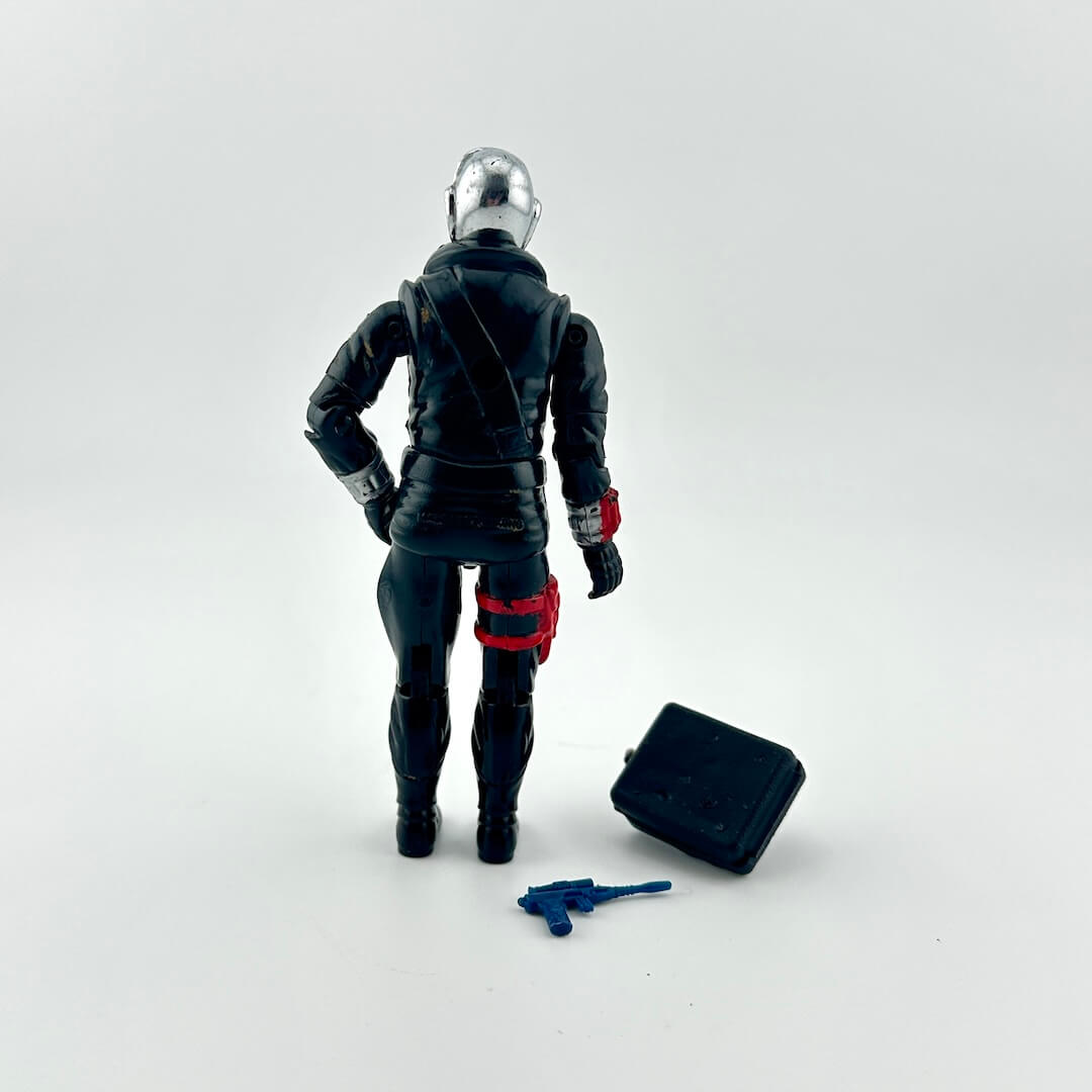 Action figure in black and red suit with a tool on a white background