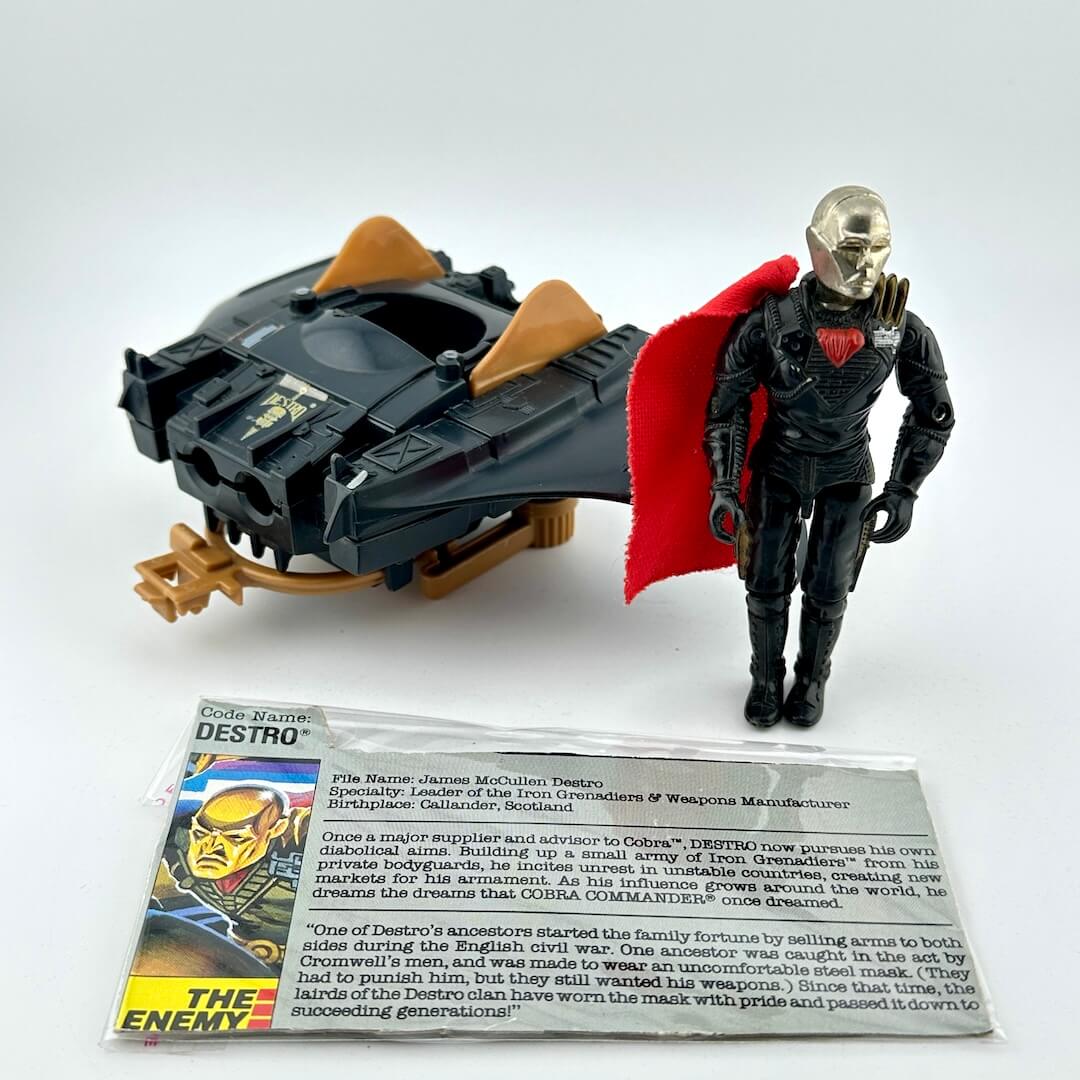 Toy figure of Destro with vehicle and character card on a white background