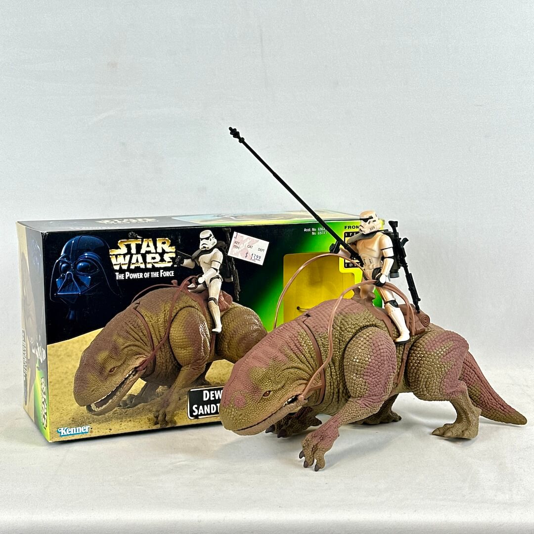 Star Wars Dewback toy with a stormtrooper figure on top, in front of a Star Wars box.