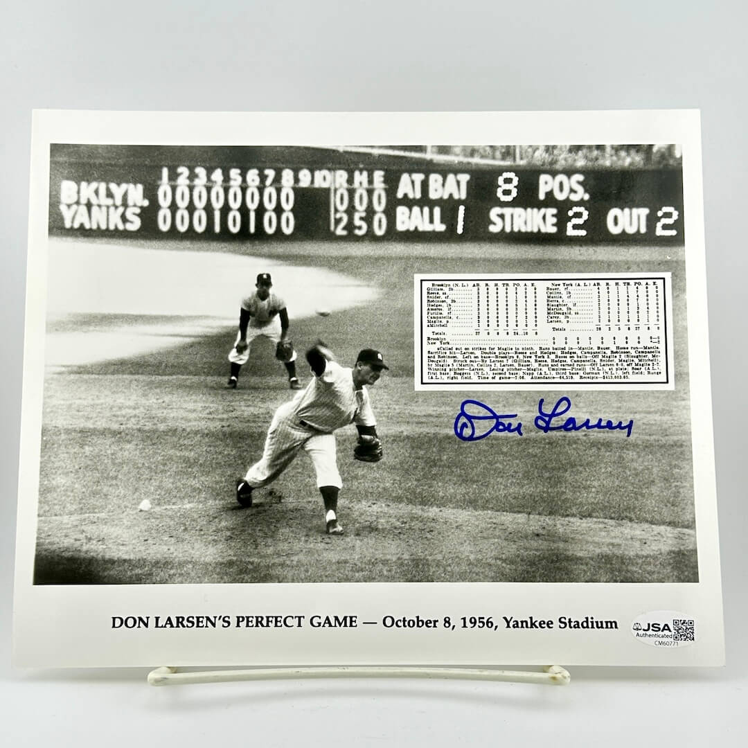 Black and white photo of Don Larsen pitching a perfect game with scoreboard and signature on display.