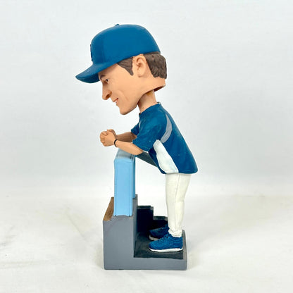 A custom bobblehead figurine of a baseball player wearing a blue cap, blue jersey, white pants, and blue sneakers.