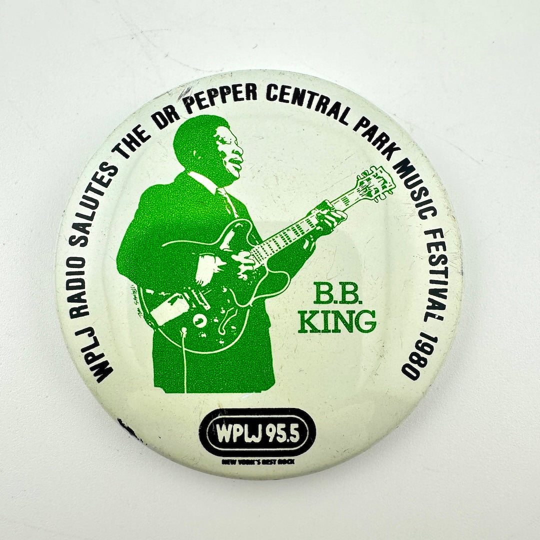 Circular pin badge with green silhouette of BB King playing guitar with black event detail text around outside. 