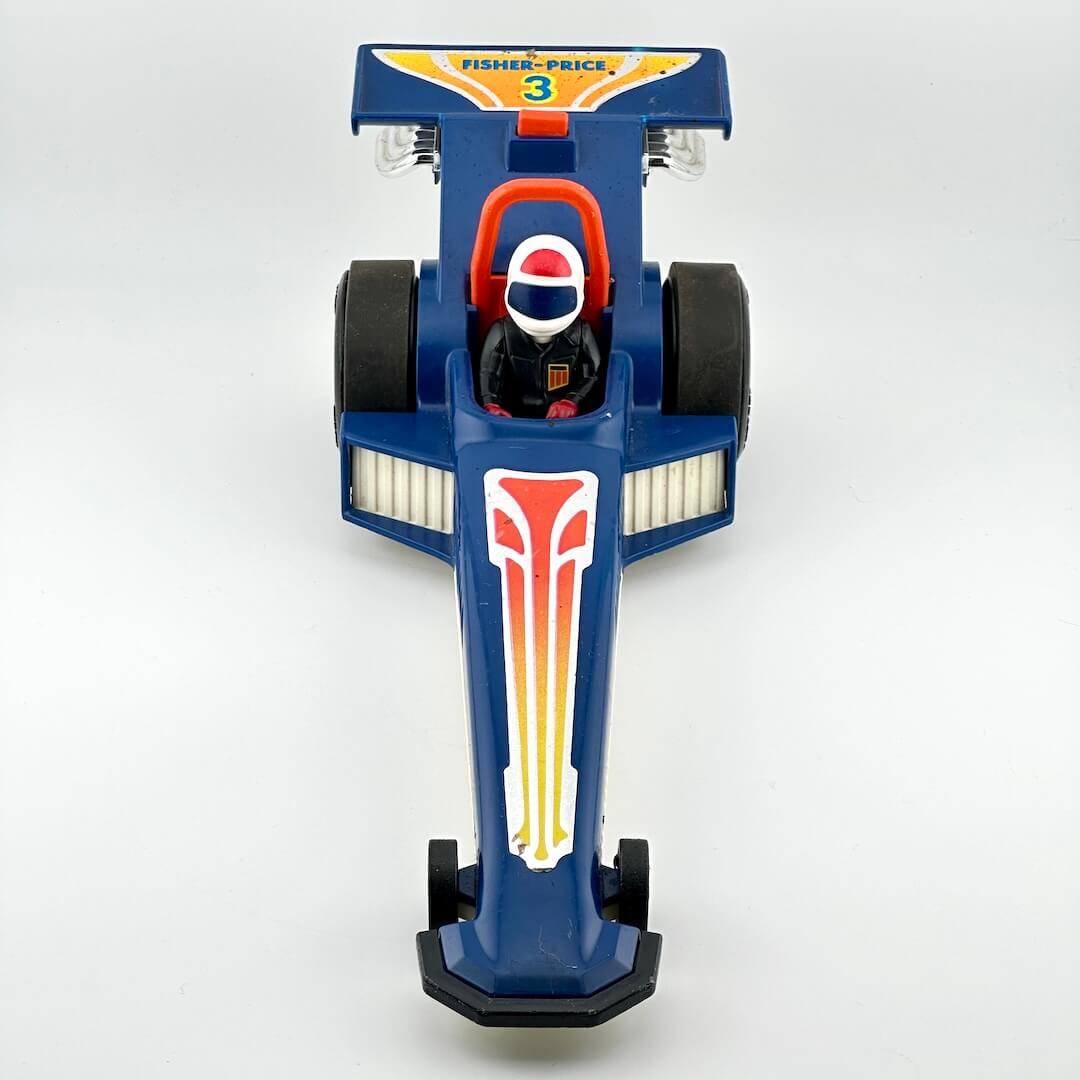 A vintage blue toy drag racer with red, yellow, and white graphics, featuring a driver figure inside.