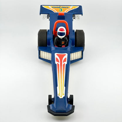 A vintage blue toy drag racer with red, yellow, and white graphics, featuring a driver figure inside.