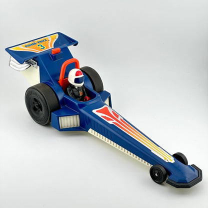 A vintage blue toy drag racer with red, yellow, and white graphics, featuring a driver figure inside.