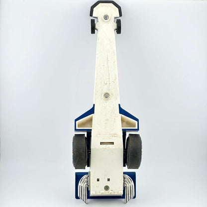 A vintage blue toy drag racer with red, yellow, and white graphics, featuring a driver figure inside.