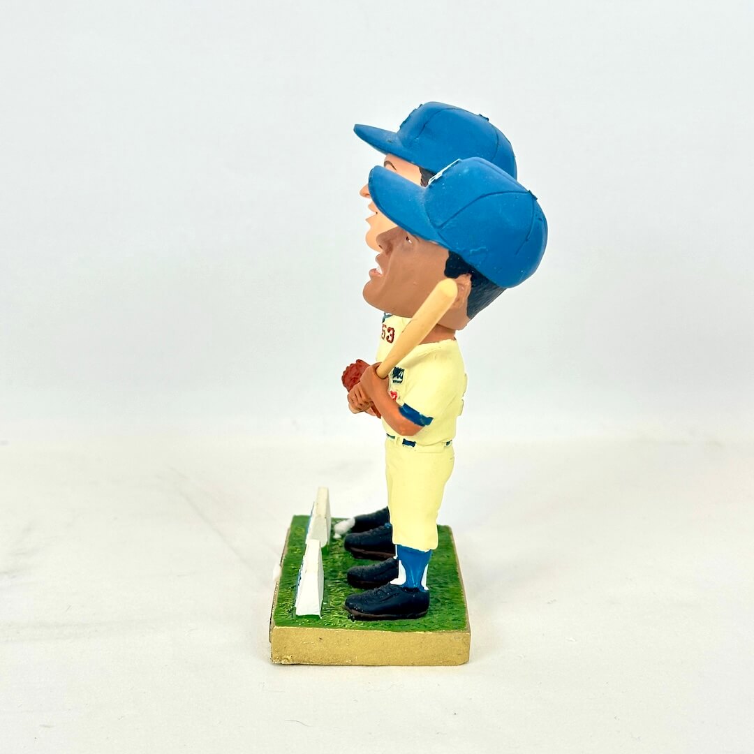 A vintage bobblehead figurine of a baseball player in a yellow uniform and blue cap.