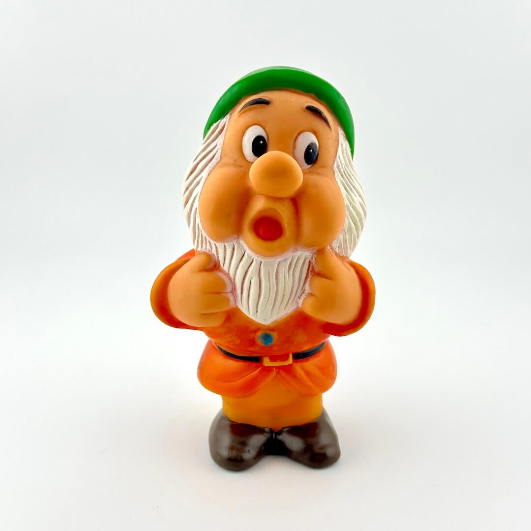Toy figure of a character with a green hat and orange outfit on a white background