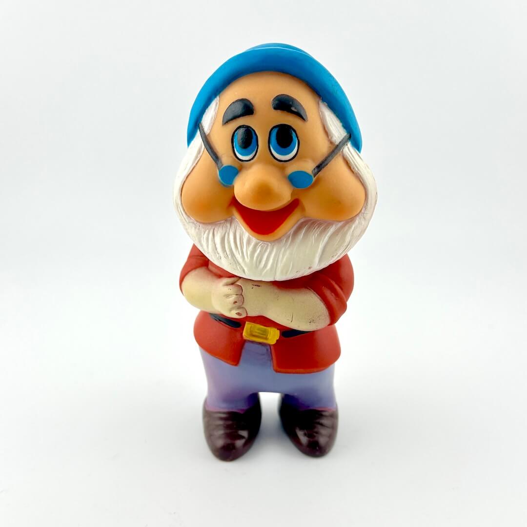Toy figure of a character with a blue hat and red outfit on a white background