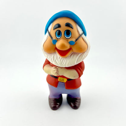 Toy figure of a character with a blue hat and red outfit on a white background